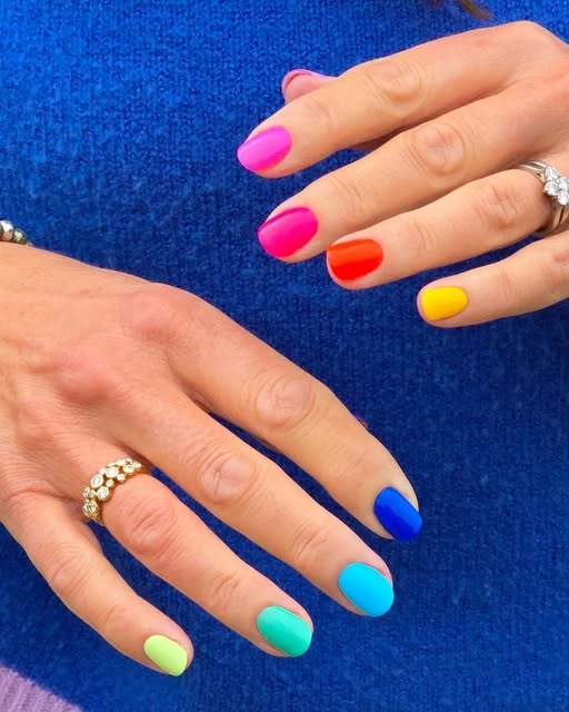 Rainbow gel manicure in pink, red, orange, yellow, green, aqua and blue on a royal-blue knit